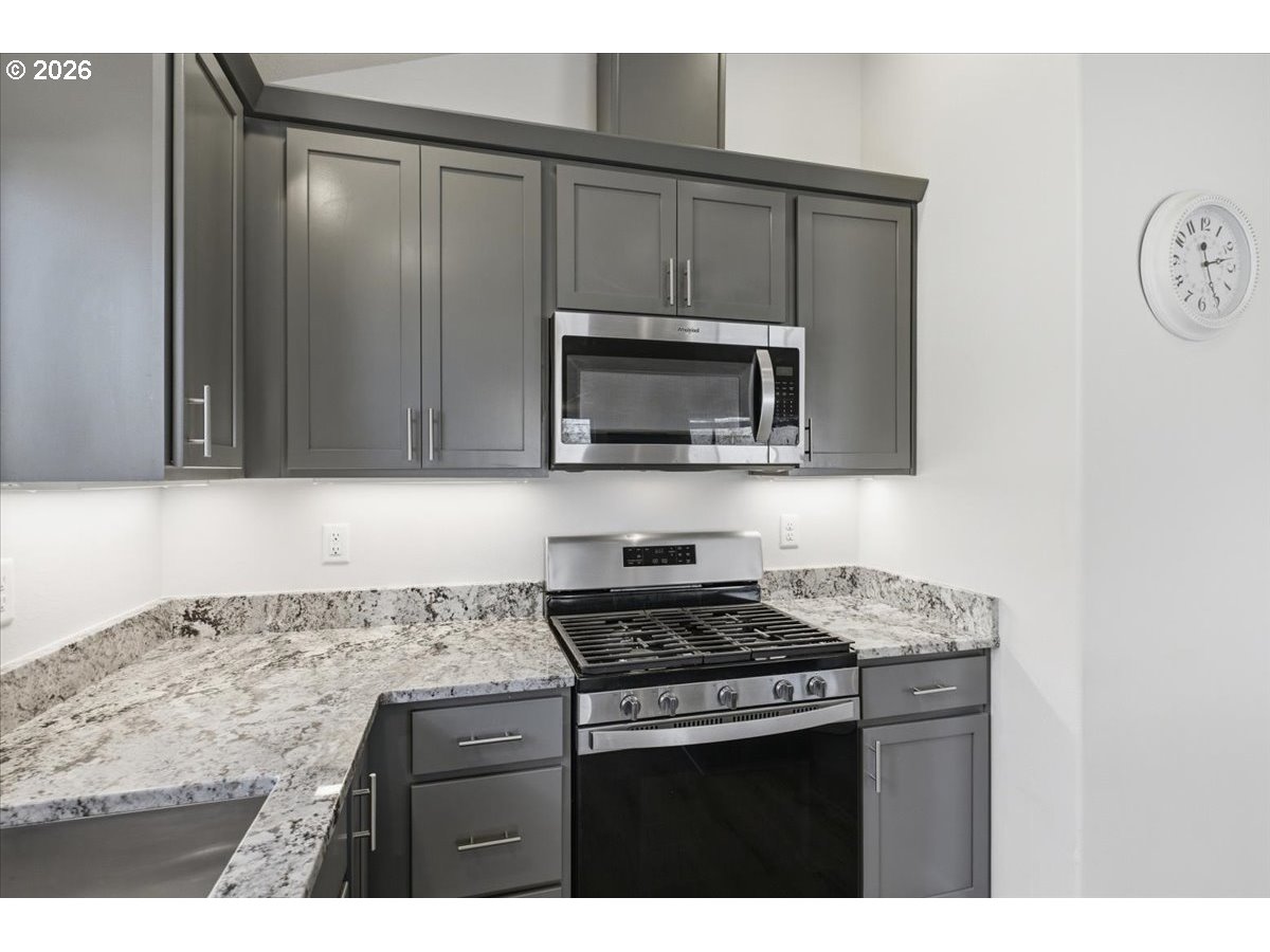 2046 Southeast Academy Street Dallas, OR 97338 - Photo 18 of 47 a kitchen with granite countertop a stove top oven microwave and cabinets