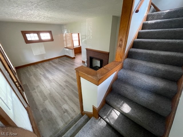 997 Berwin Street Akron, OH 44310 - Photo 28 of 34 Stairway featuring hardwood floors, a fireplace, and a textured ceiling
