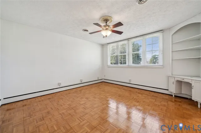 an empty room with chandelier fan and windows