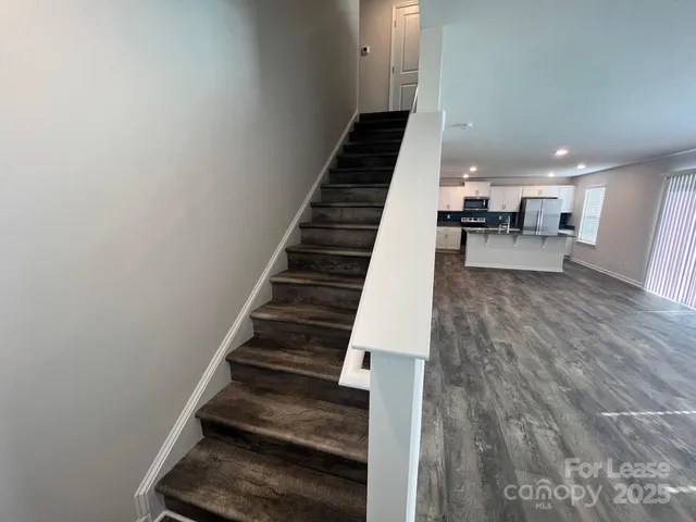 a view of a hallway with wooden floor and staircase