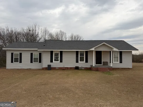 a front view of house with yard and trees in the background