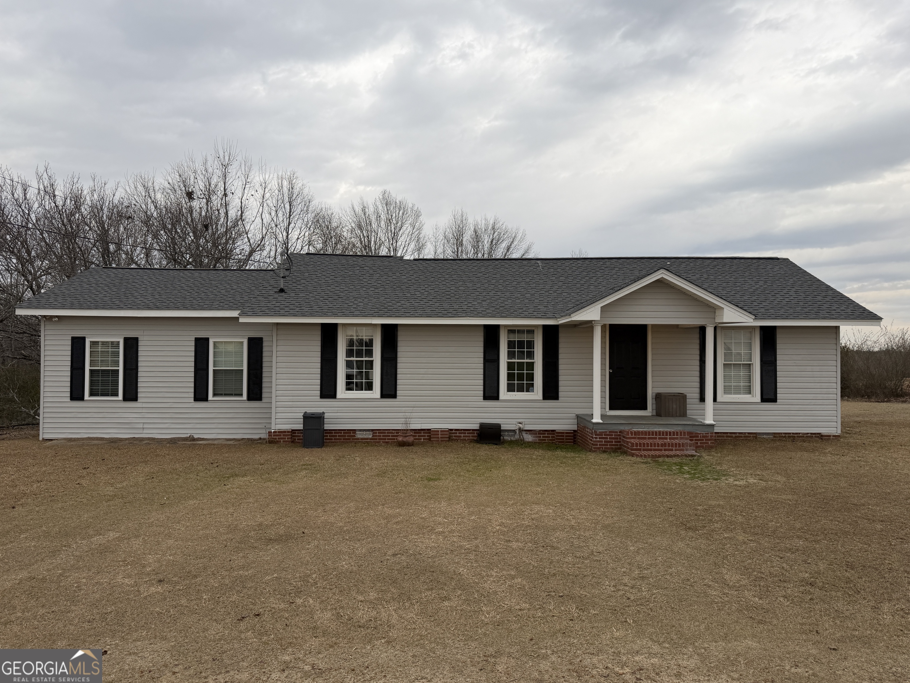 a front view of house with yard and trees in the background