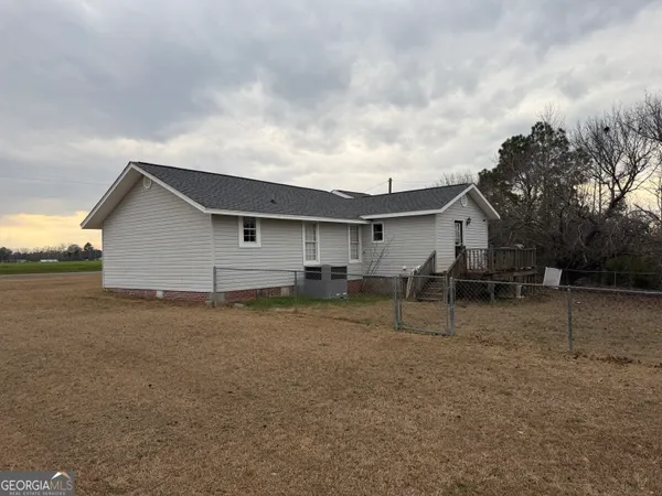 a view of house with a dry yard and covered with trees