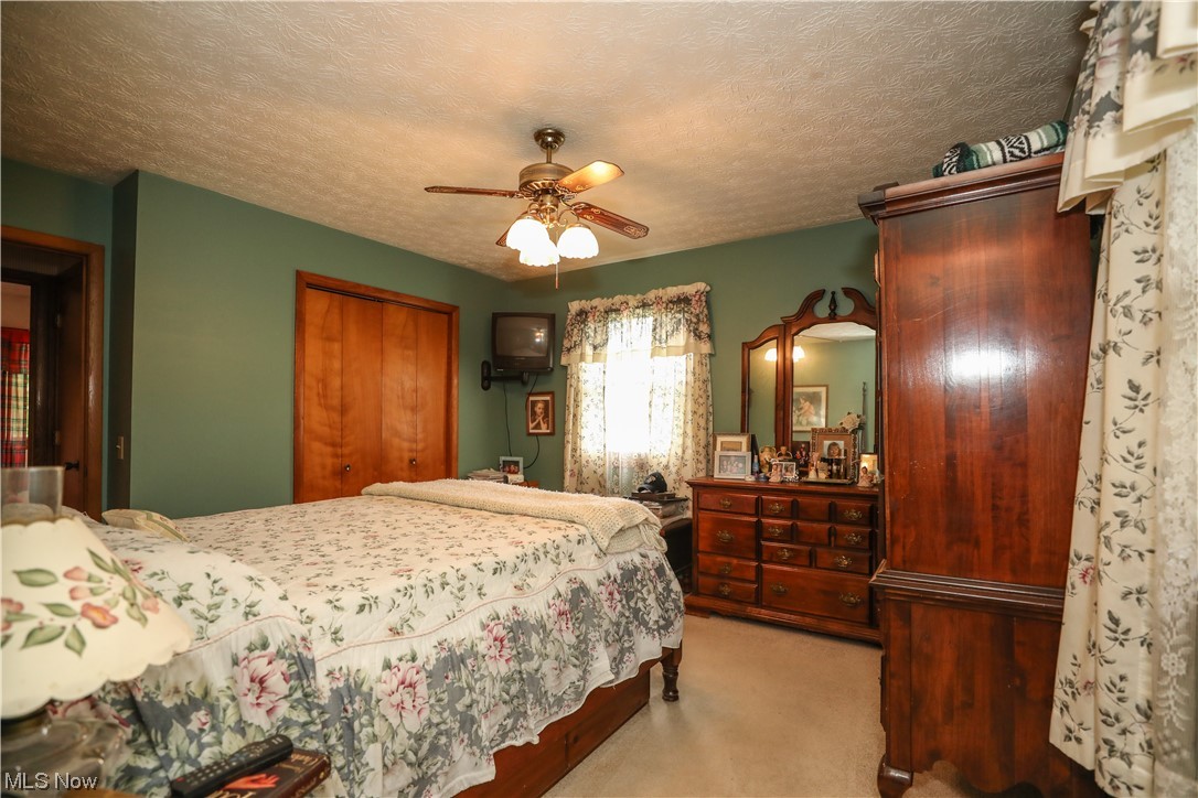 5344 Camp Road Ravenna, OH 44266 - Photo 14 of 30 Bedroom featuring ceiling fan, light carpet, and a textured ceiling