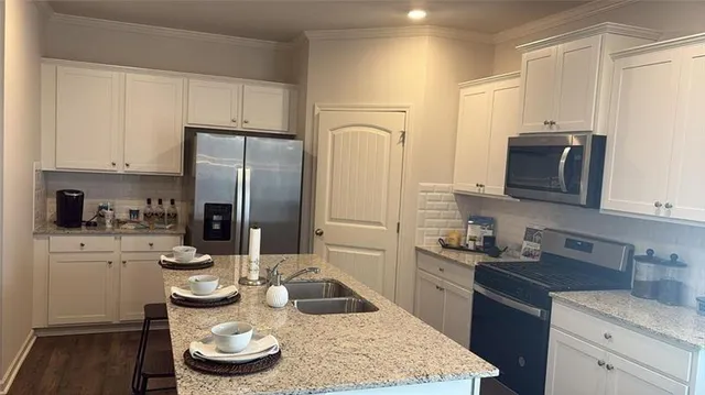 a kitchen with stainless steel appliances kitchen island granite countertop a sink stove and refrigerator