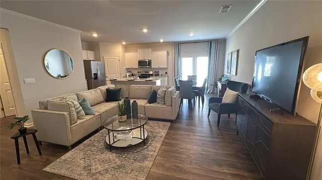 a living room with furniture kitchen view and a wooden floor