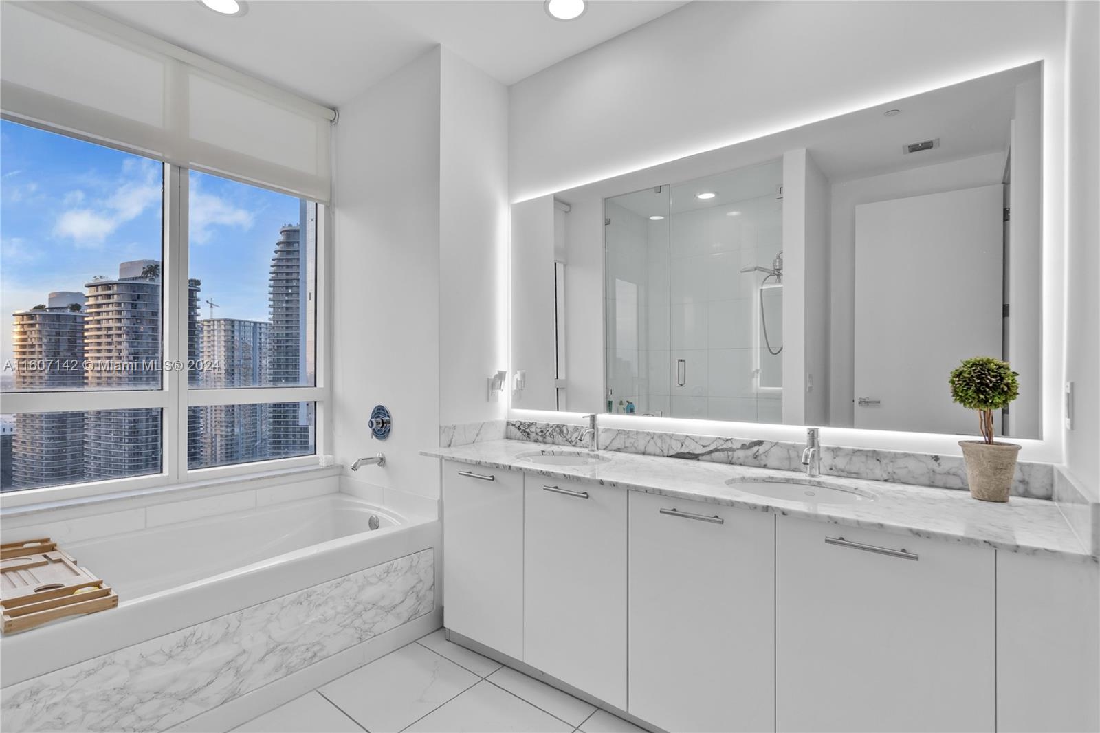 951 Brickell Avenue, Unit PH4111 Miami, FL 33131 - Photo 10 of 32 a bathroom with a granite countertop tub sink and mirror