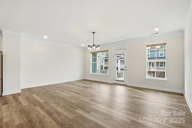 an empty room with wooden floor cabinet and windows