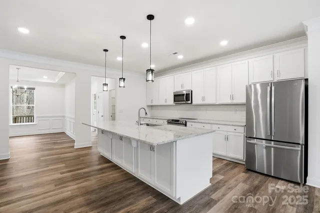 a kitchen with stainless steel appliances a refrigerator and a wooden floor