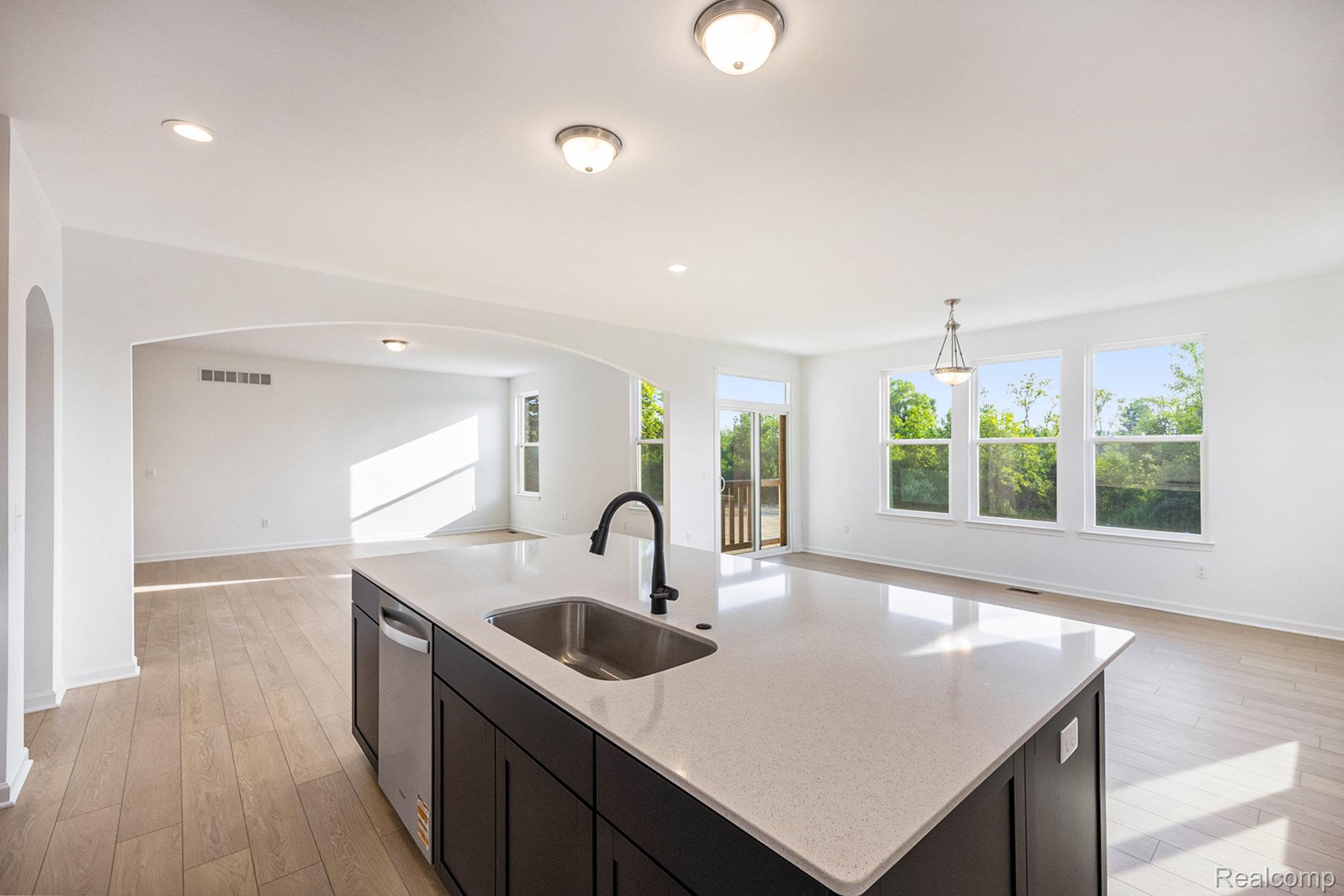 68788 Place Road New Haven, MI 48050 - Photo 29 of 29 Kitchen with open floor plan, light wood finished floors, pendant lighting, a center island with sink, and light stone countertops