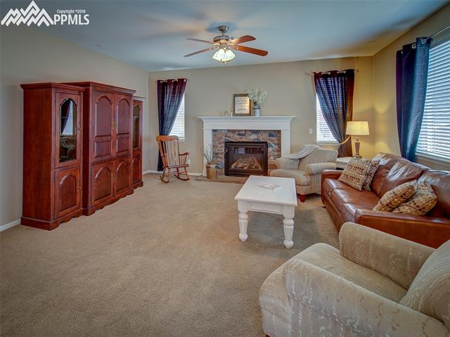 829 Spectrum Loop Colorado Springs, CO 80921 - Photo 7 of 19 Living room has gas fireplace, ceiling fan and is wired for surround sound.