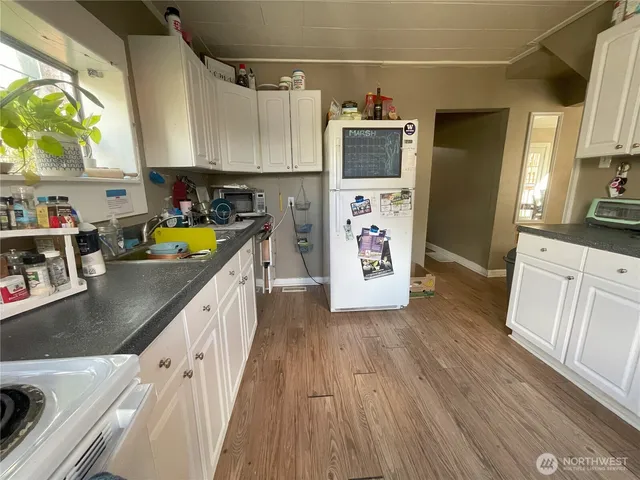 a kitchen with stainless steel appliances a microwave a stove a sink dishwasher and cabinets with wooden floor