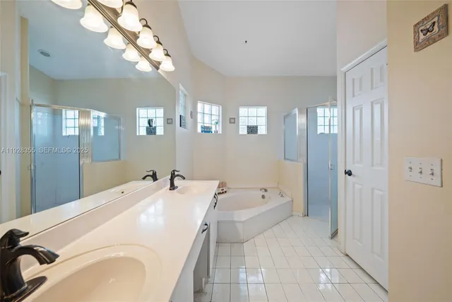 a bathroom with a tub a double vanity sink and a mirror