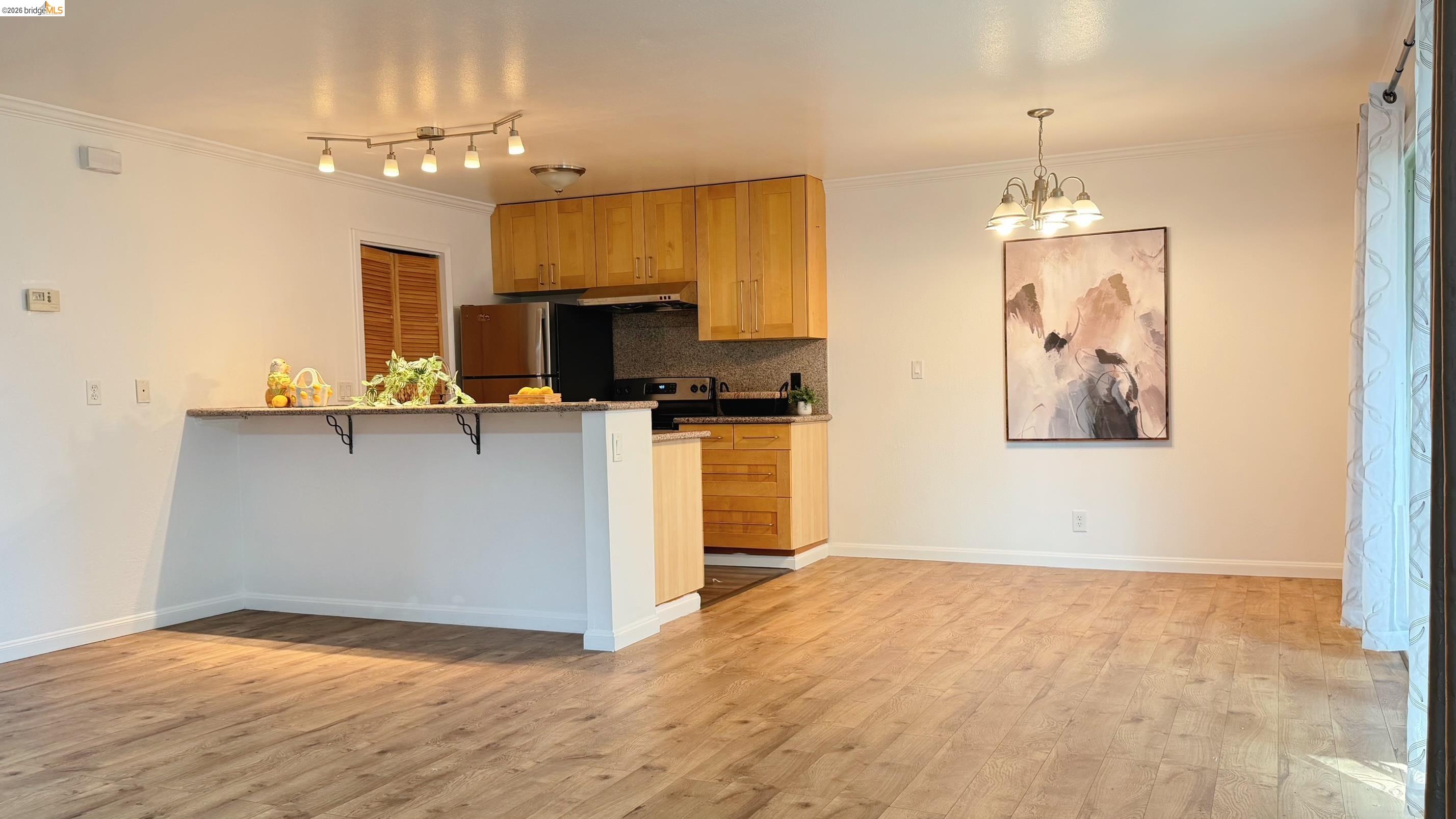 9085 Alcosta Boulevard, Unit 331 San Ramon, CA 94583 - Photo 3 of 18 Kitchen with a peninsula, crown molding, a kitchen breakfast bar, hanging lights, and light wood finished floors