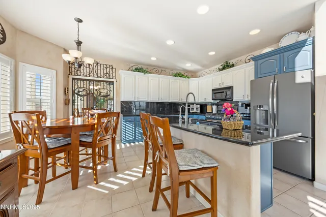 a kitchen with stainless steel appliances kitchen island granite countertop a dining table chairs stove and refrigerator