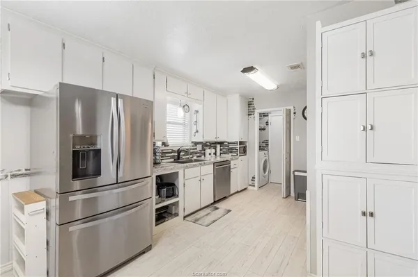 a kitchen with stainless steel appliances a refrigerator stove and white cabinets