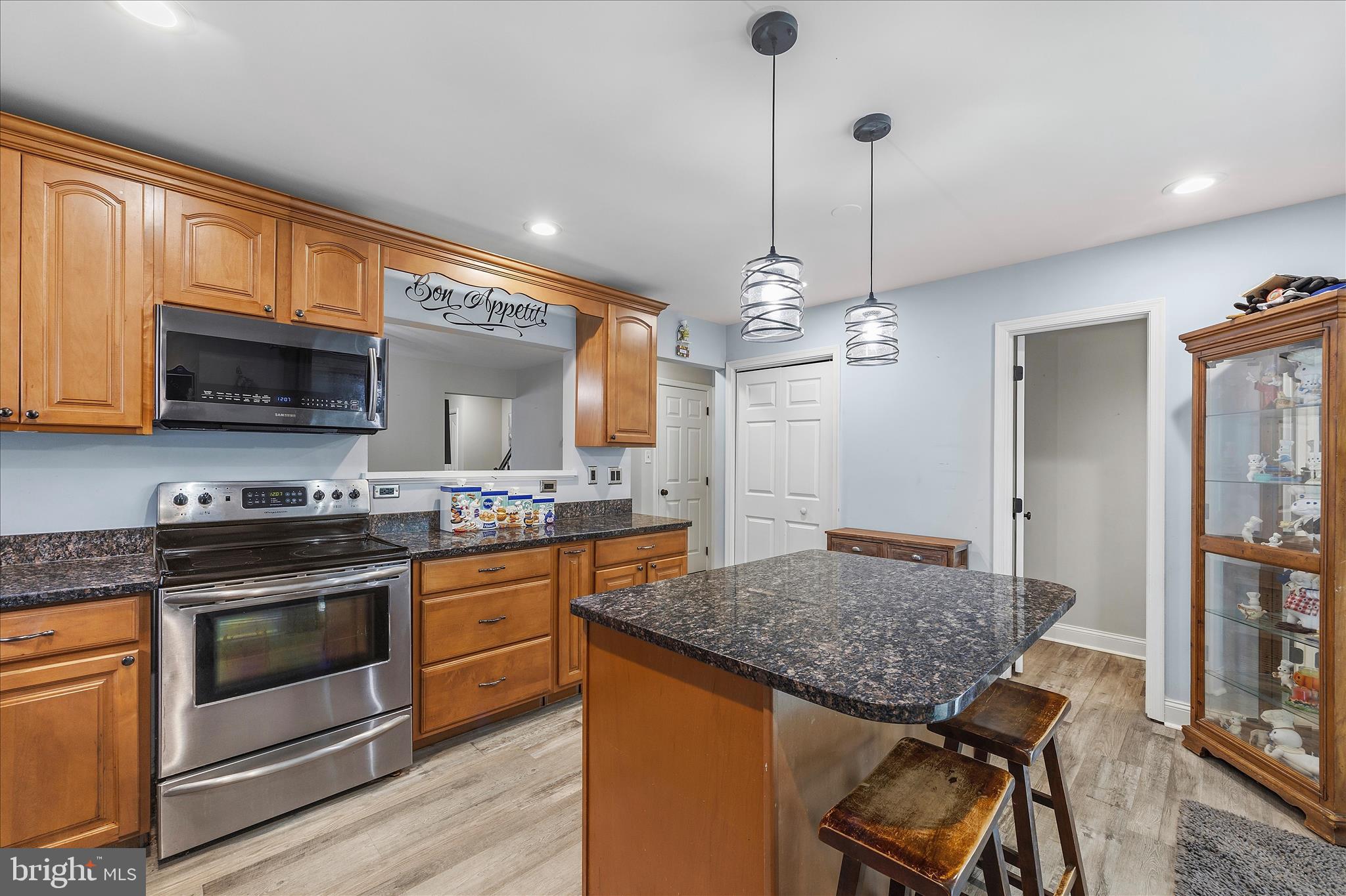 2209 227th Street Pasadena, MD 21122 - Photo 13 of 42 a kitchen with stainless steel appliances granite countertop a stove top oven a sink dishwasher a dining table and chairs with wooden floor