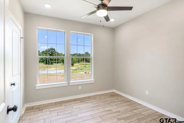 a view of an empty room with a window and wooden floor