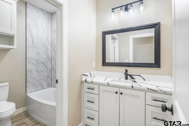 a bathroom with a bathtub sink vanity mirror and toilet