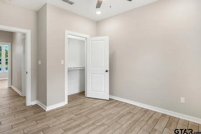 a view of an empty room with wooden floor and a bathroom