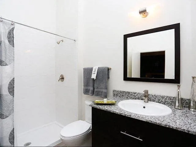 a bathroom with a granite countertop sink toilet and shower