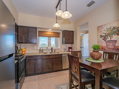 5075 Harmony Circle, Unit 302 Vero Beach, FL 32967 - Photo 12 of 32 a kitchen with stainless steel appliances a dining table and chairs