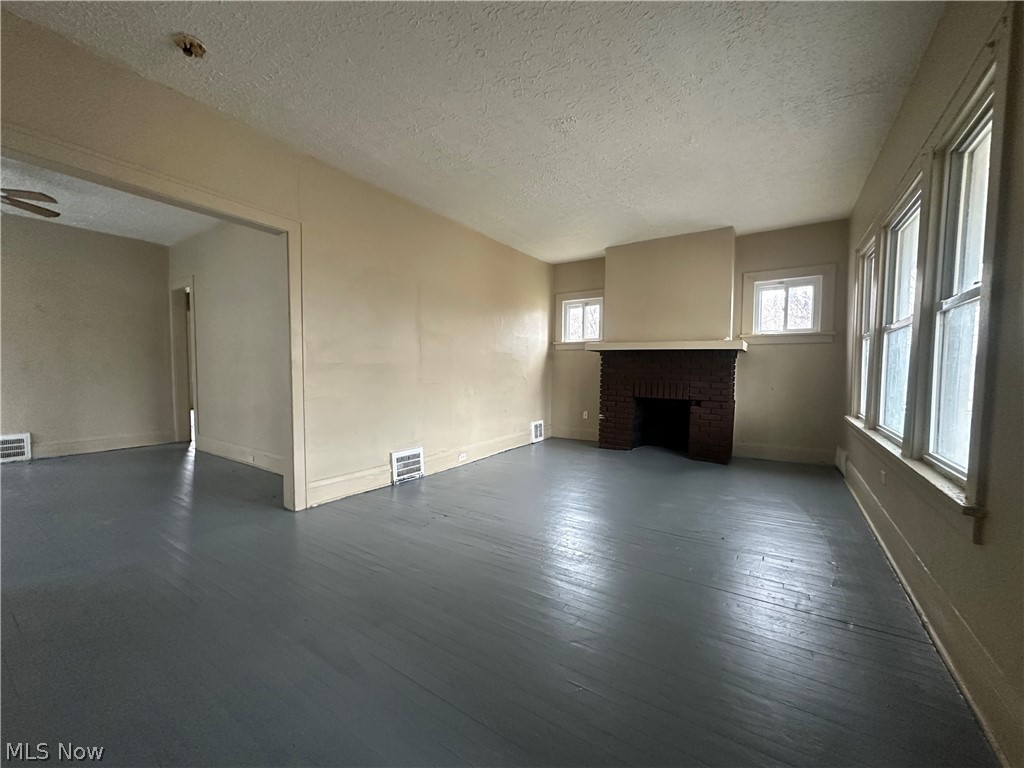 13510 Coit Road Cleveland, OH 44110 - Photo 2 of 12 Unfurnished living room featuring dark wood-type flooring, a textured ceiling, and a fireplace
