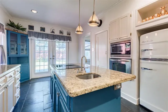 a kitchen with granite countertop kitchen island stainless steel appliances a sink stove and refrigerator