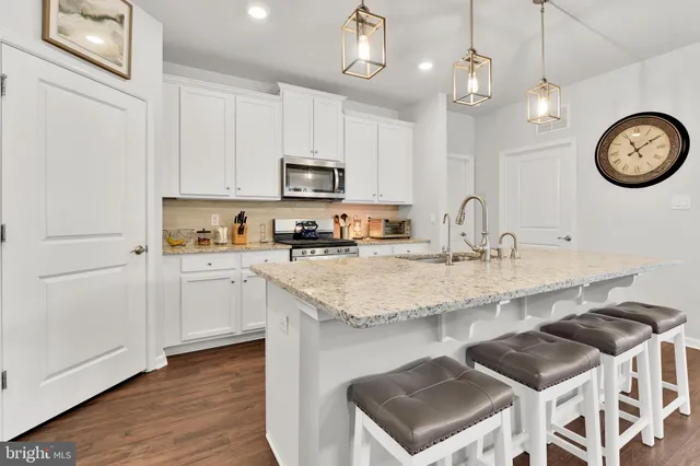 a kitchen with stainless steel appliances granite countertop a sink a stove a refrigerator cabinets and chairs