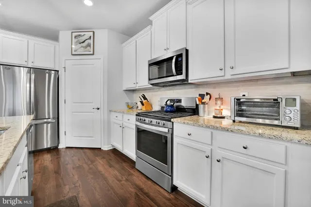 a kitchen with stainless steel appliances white cabinets and a refrigerator