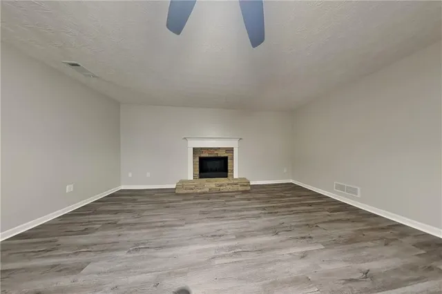 a view of an empty room with wooden floor and a fireplace