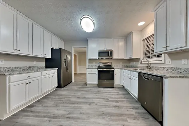 a kitchen with granite countertop a refrigerator stove top oven and sink