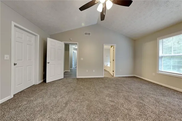 an empty room with chandelier fan and windows
