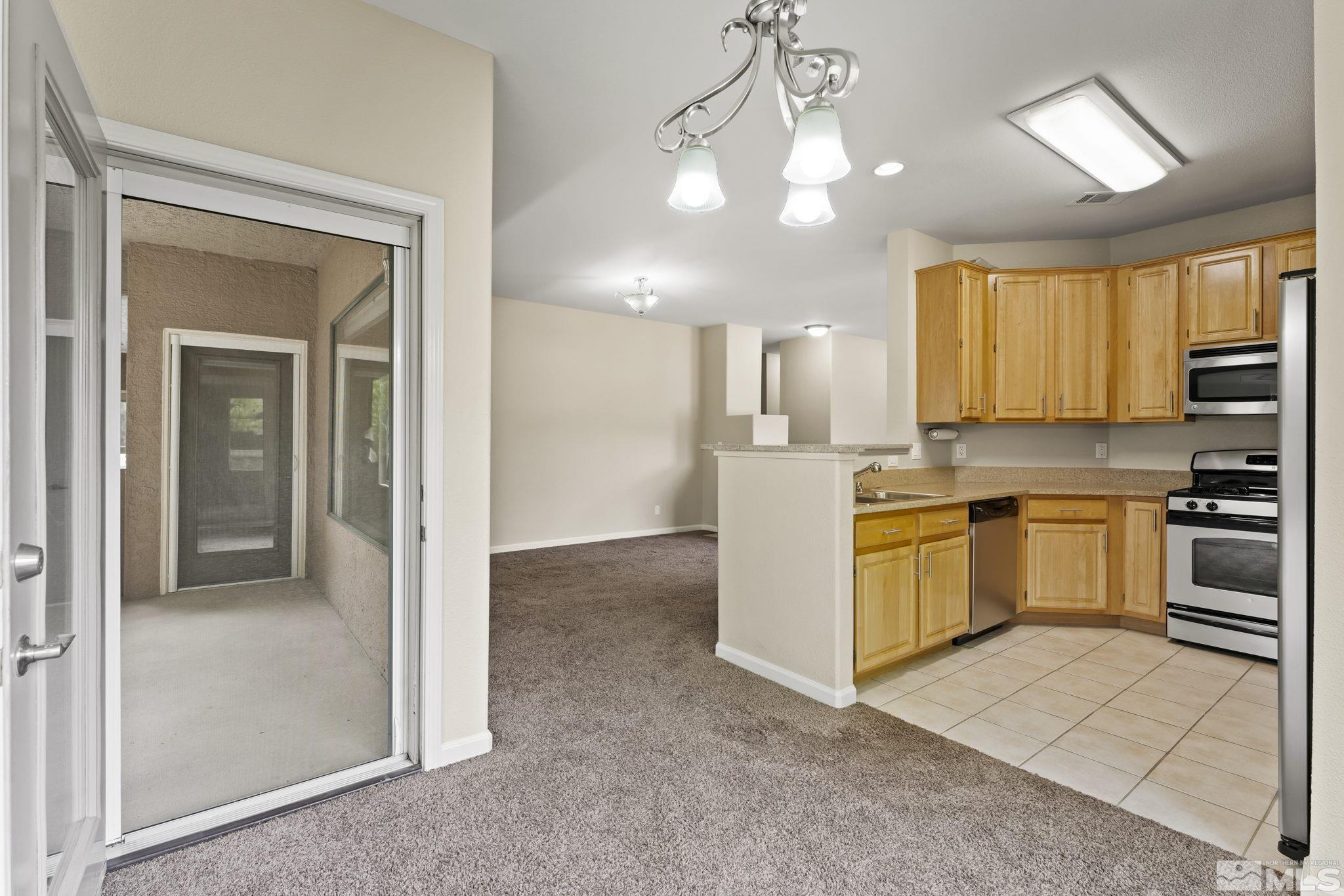 900 South Meadows Parkway, Unit 321 Reno, NV 89521 - Photo 5 of 40 a kitchen with a refrigerator a stove top oven and a sink with wooden floor