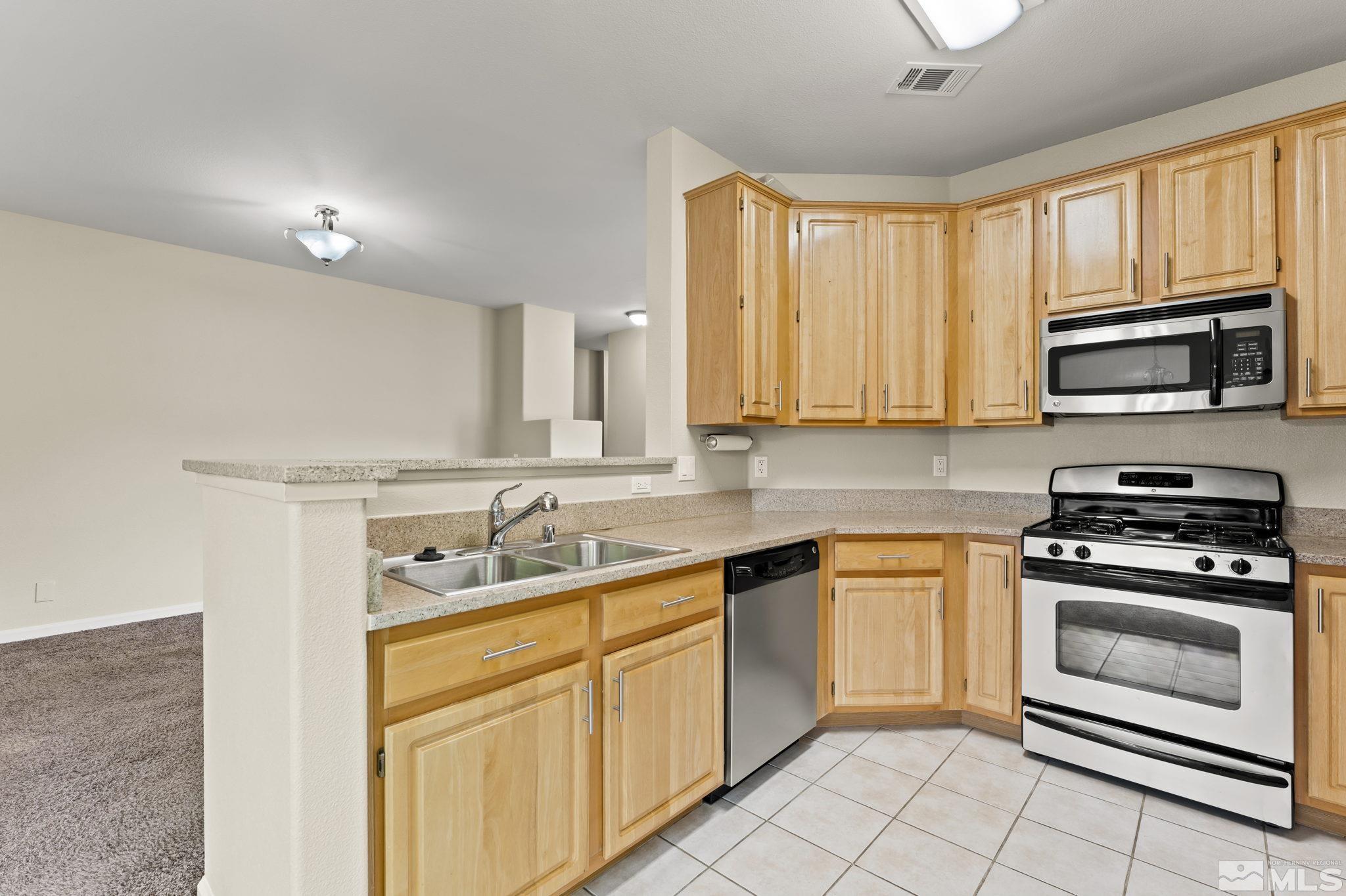 900 South Meadows Parkway, Unit 321 Reno, NV 89521 - Photo 6 of 40 a kitchen with stainless steel appliances granite countertop white cabinets a sink and a stove