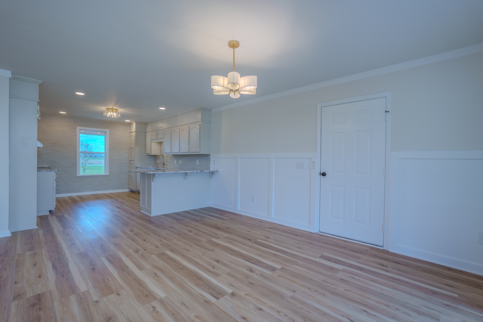 105 Peppertown Road Loretto, TN 38469 - Photo 11 of 37 an empty room with wooden floor kitchen view and a chandelier
