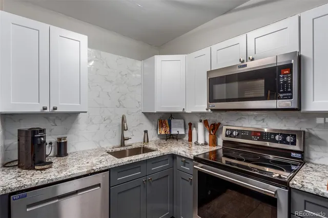 a kitchen with granite countertop a sink stove and microwave