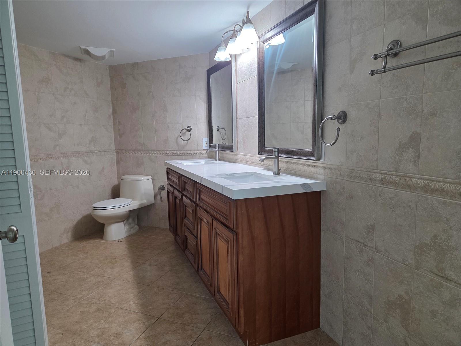 5880 Collins Avenue, Unit 806 Miami Beach, FL 33140 - Photo 11 of 30 a bathroom with a double vanity sink toilet and a mirror