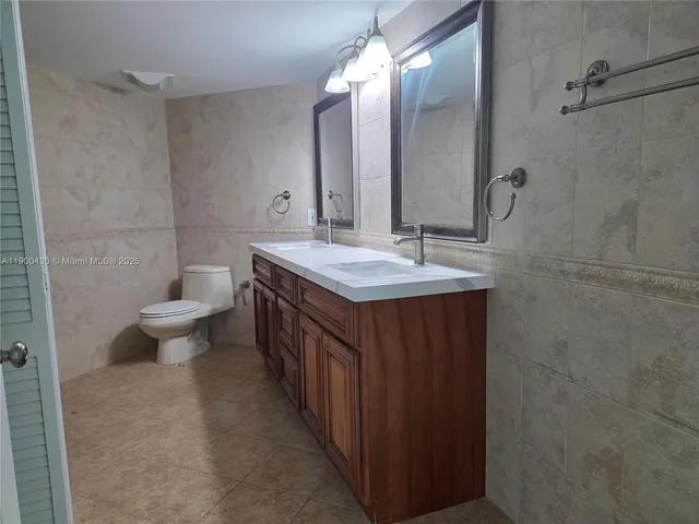 a bathroom with a granite countertop sink a toilet and a mirror
