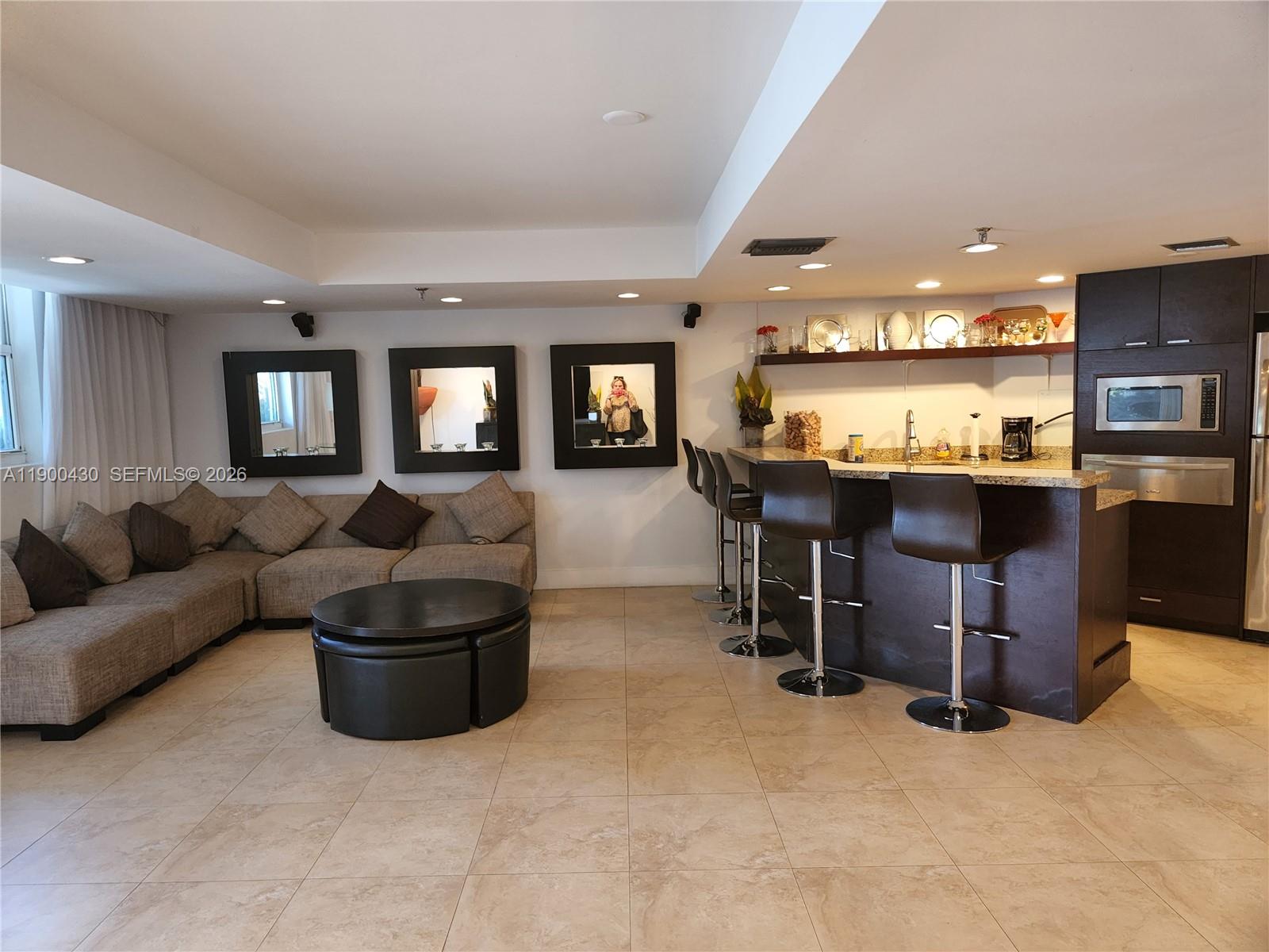 5880 Collins Avenue, Unit 806 Miami Beach, FL 33140 - Photo 26 of 30 a living room with lots of furniture and a refrigerator