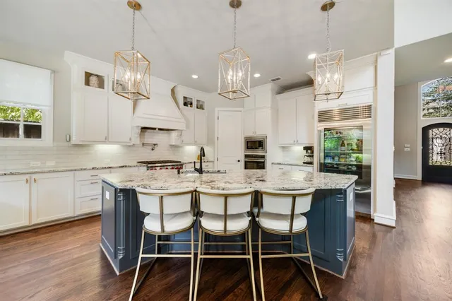 a kitchen with granite countertop white cabinets and stainless steel appliances