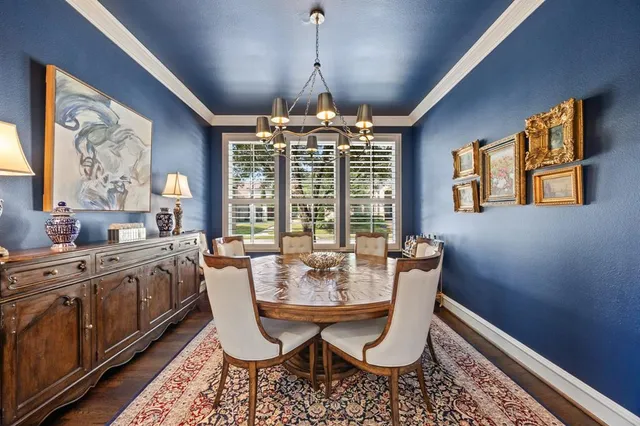 a dining room with wooden floor a chandelier a wooden table and chairs