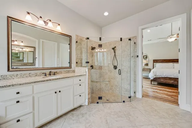 a bathroom with a granite countertop sink two mirror and a shower
