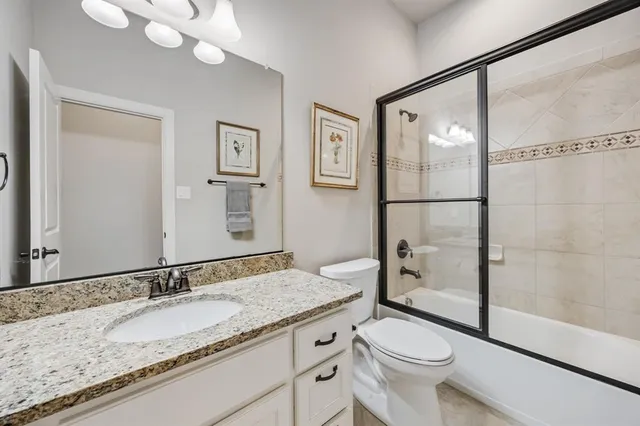a bathroom with a granite countertop sink mirror vanity and toilet