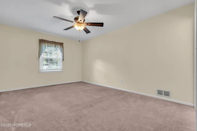 an empty room with windows and ceiling fan