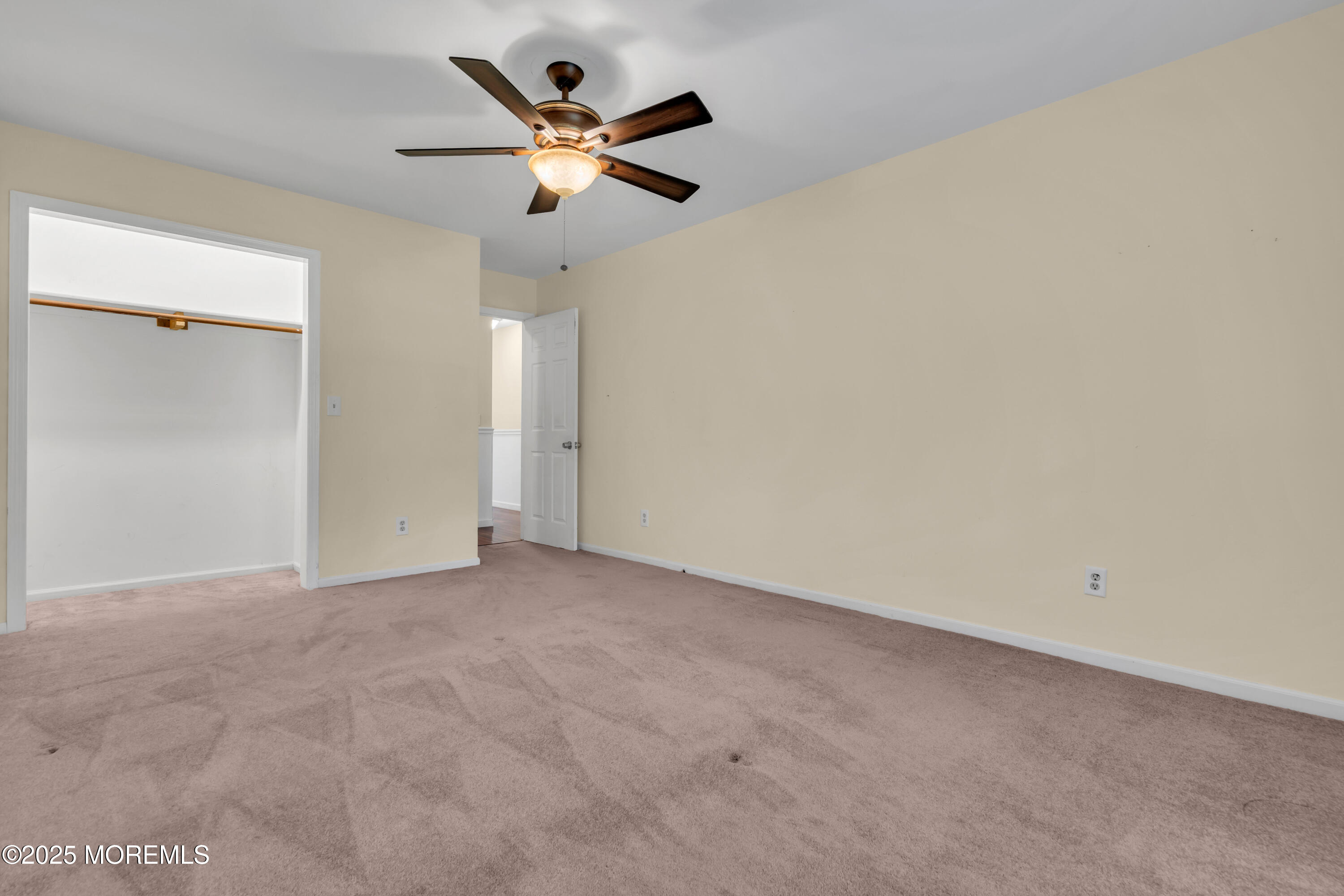 638 Freehold Road Jackson, NJ 08527 - Photo 48 of 61 an empty room with a chandelier fan and a kitchen view