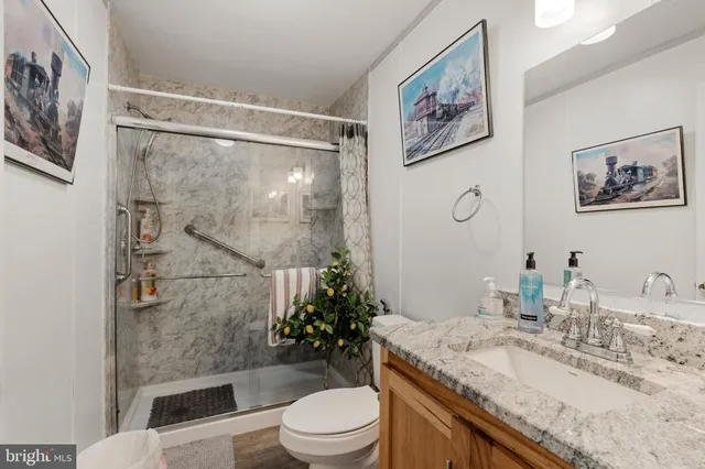a bathroom with a granite countertop sink toilet a mirror and shower