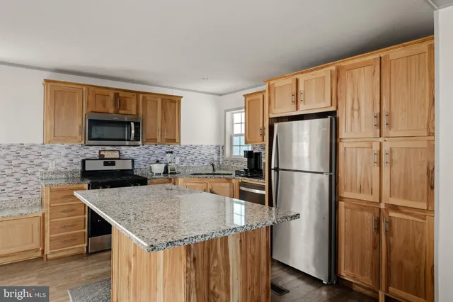 a kitchen with stainless steel appliances granite countertop a refrigerator a stove a sink and a microwave