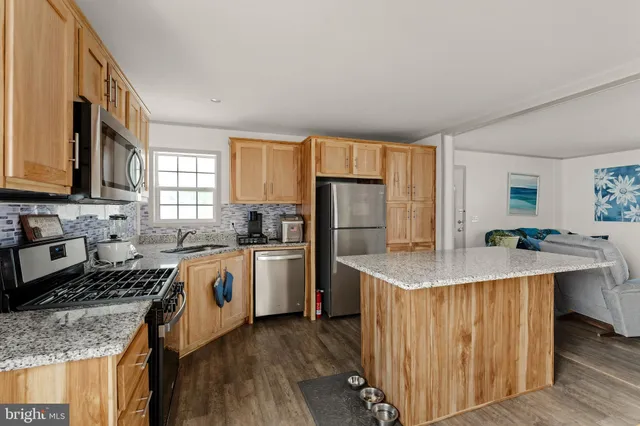 a kitchen with stainless steel appliances granite countertop a sink stove refrigerator and cabinets