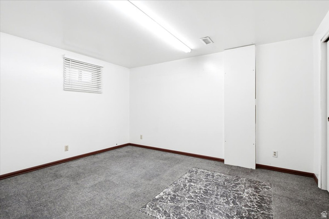 7050 South 260 East Midvale, UT 84047 - Photo 24 of 28 Spacious interior featuring white walls, gray carpet, dark wood baseboards, a window with blinds, and fluorescent ceiling lighting